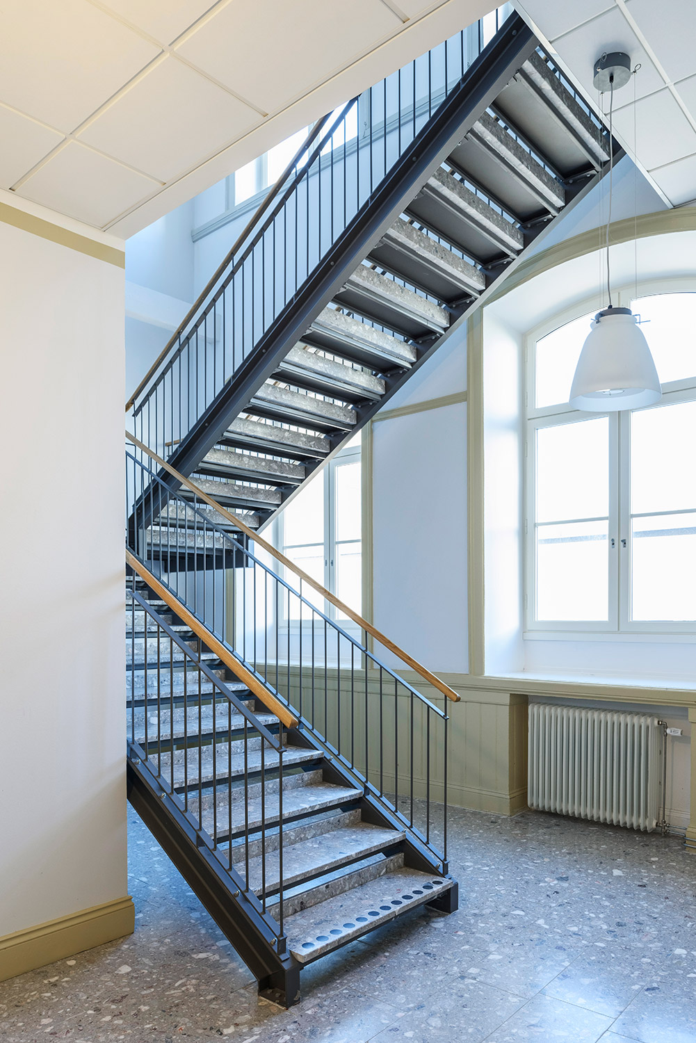 Raka trappor interiört – Rak trappa med betongsteg och trähandledare.