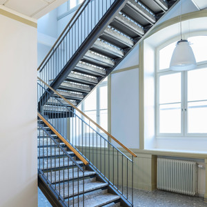 Raka trappor interiört – Rak trappa med betongsteg och trähandledare.