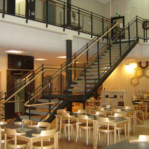 Raka trappor design – Trappa med terrazzosteg, räcke med nät och trähandledare.